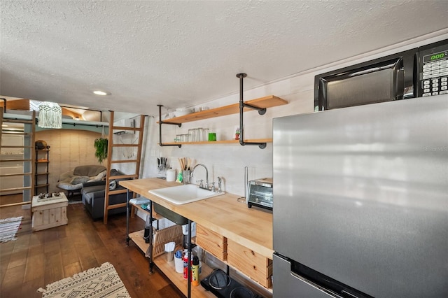 kitchen featuring a textured ceiling, dark wood-type flooring, a sink, and freestanding refrigerator