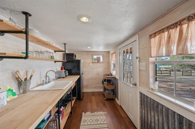 kitchen featuring dark wood-style floors, freestanding refrigerator, a textured ceiling, open shelves, and a sink