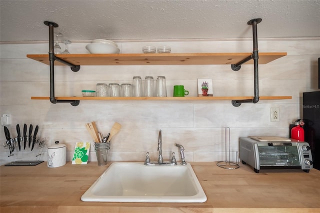 kitchen with a textured ceiling, open shelves, a sink, and a toaster