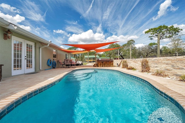 view of swimming pool with a patio area, outdoor dry bar, a fenced in pool, and french doors