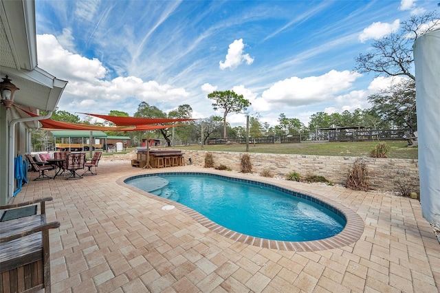 pool with a patio area, fence, and outdoor dining space