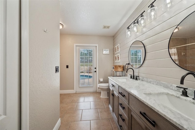 bathroom with visible vents, double vanity, a sink, and toilet