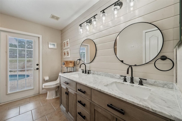 bathroom featuring visible vents, a sink, toilet, and double vanity