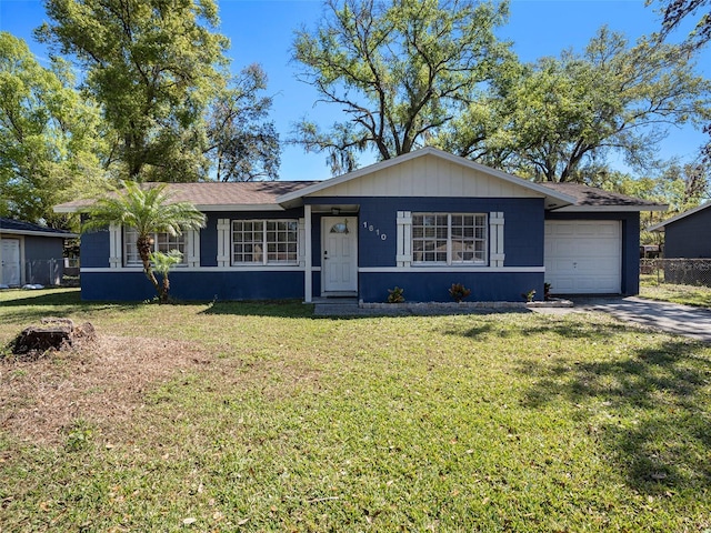 ranch-style home featuring driveway, an attached garage, and a front yard