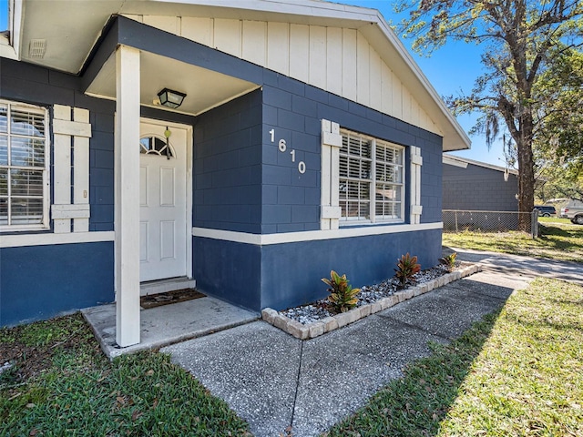 entrance to property with concrete block siding and fence