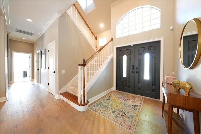 foyer with visible vents, crown molding, baseboards, stairway, and hardwood / wood-style floors