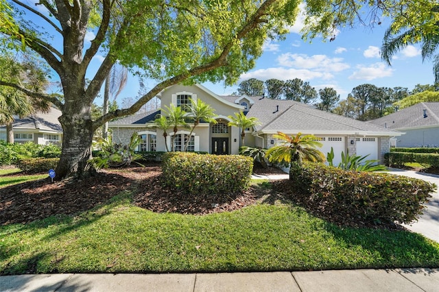 view of front facade featuring stucco siding, an attached garage, concrete driveway, and a front lawn