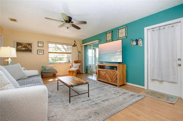 living room with visible vents, a ceiling fan, a textured ceiling, wood finished floors, and baseboards