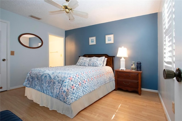 bedroom featuring visible vents, a ceiling fan, a textured ceiling, wood finished floors, and baseboards