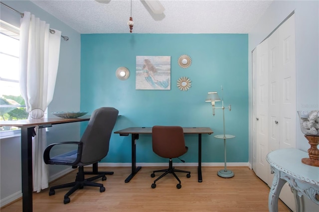 home office with a textured ceiling, baseboards, and wood finished floors