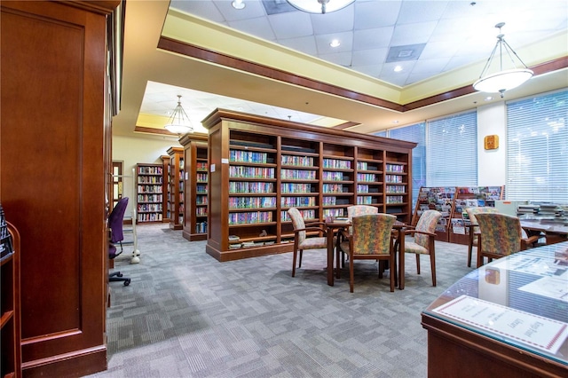 carpeted office featuring a tray ceiling, wall of books, and recessed lighting