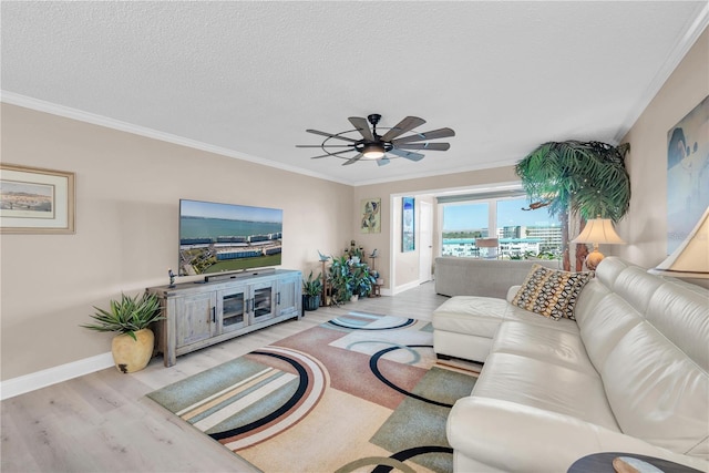 living room with a textured ceiling, wood finished floors, a ceiling fan, baseboards, and ornamental molding