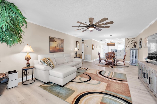 living area featuring a textured ceiling, light wood finished floors, visible vents, and crown molding