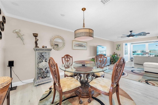 dining space with baseboards, visible vents, a ceiling fan, ornamental molding, and wood finished floors