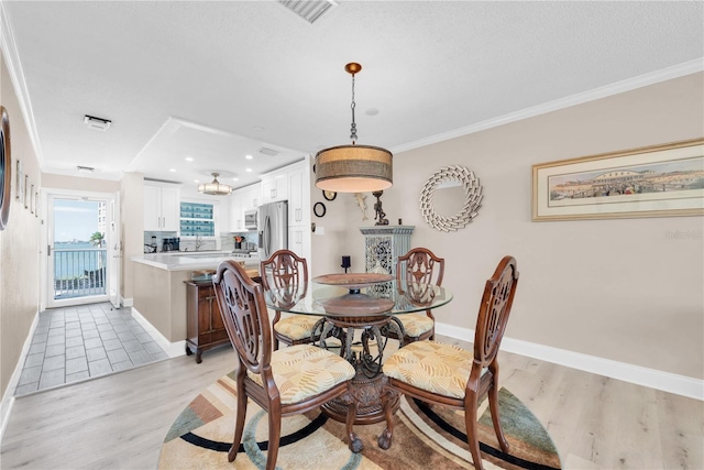 dining room with light wood finished floors, baseboards, visible vents, crown molding, and recessed lighting