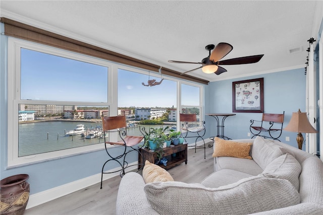 living area featuring baseboards, wood finished floors, visible vents, and crown molding