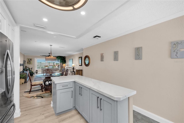 kitchen with baseboards, light wood-type flooring, gray cabinets, freestanding refrigerator, and crown molding