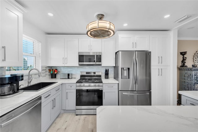 kitchen featuring stainless steel appliances, backsplash, a sink, and visible vents