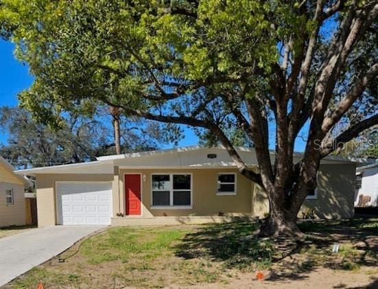 ranch-style home with driveway, an attached garage, and stucco siding