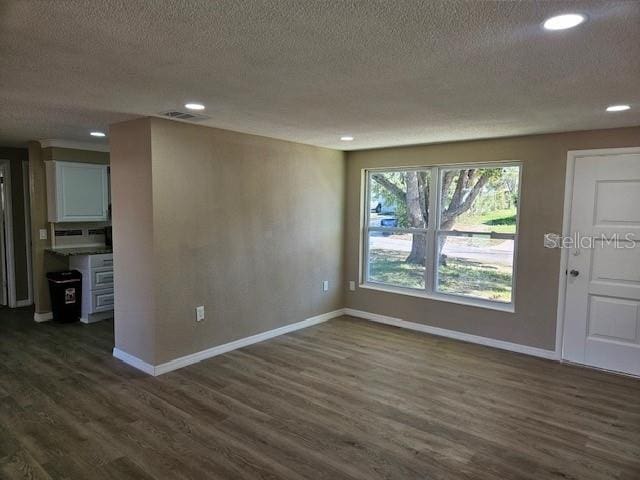 unfurnished room featuring dark wood-style floors, recessed lighting, a textured ceiling, and baseboards