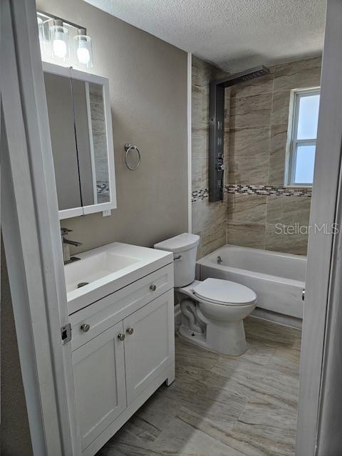 bathroom featuring a textured ceiling,  shower combination, vanity, and toilet