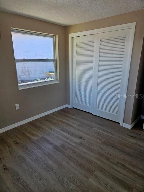 unfurnished bedroom with dark wood finished floors and baseboards