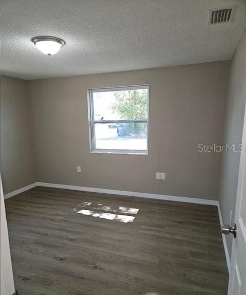 unfurnished room with dark wood-style floors, baseboards, and visible vents