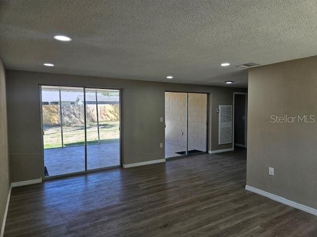 empty room featuring dark wood-type flooring, visible vents, and baseboards