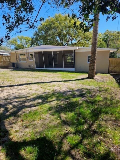 rear view of house with a sunroom, fence, and a lawn