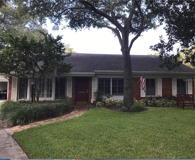 ranch-style house with brick siding, a front lawn, and roof with shingles