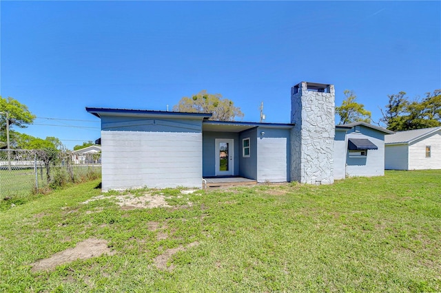 back of house featuring a yard, fence, and a chimney