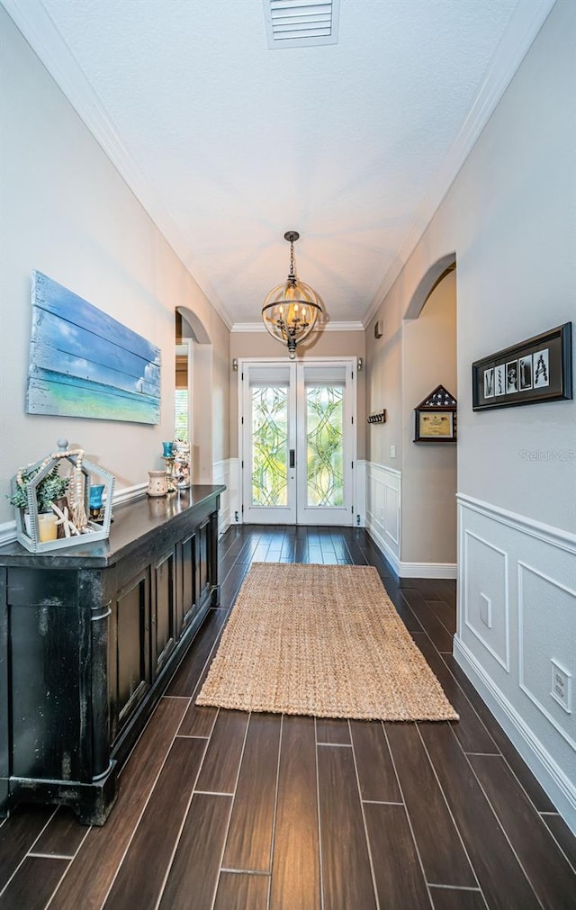 interior space featuring arched walkways, visible vents, ornamental molding, wood tiled floor, and wainscoting