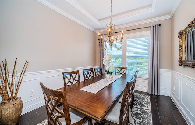 dining room featuring an inviting chandelier, a raised ceiling, dark wood finished floors, and a wainscoted wall