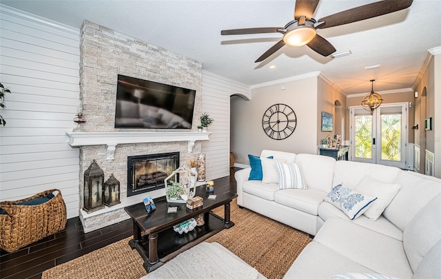 living room with ceiling fan, a fireplace, wood finished floors, french doors, and crown molding