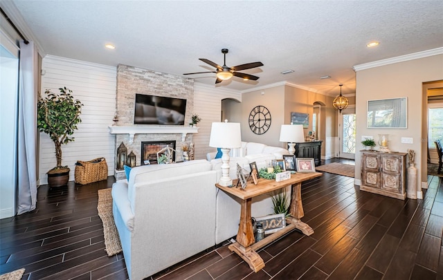 living room featuring a textured ceiling, ornamental molding, a fireplace, and wood tiled floor