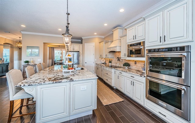 kitchen with light stone counters, a kitchen breakfast bar, black electric stovetop, custom exhaust hood, and stainless steel double oven