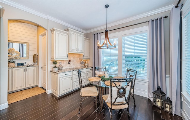 dining space with arched walkways, ornamental molding, wood finish floors, and an inviting chandelier