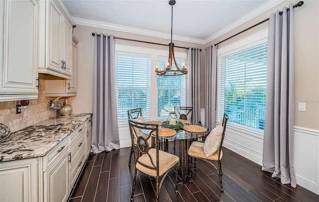 dining space featuring a chandelier, ornamental molding, wood finish floors, and baseboards