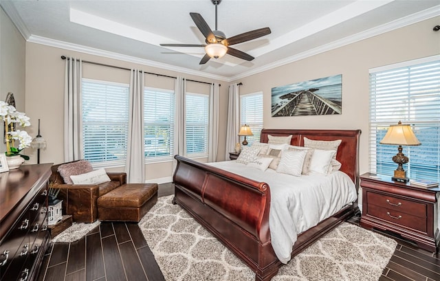 bedroom featuring baseboards, dark wood finished floors, a raised ceiling, ceiling fan, and ornamental molding