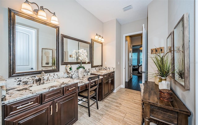 bathroom featuring double vanity, visible vents, a sink, and wood finish floors