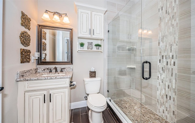 bathroom featuring a stall shower, baseboards, toilet, wood finished floors, and vanity