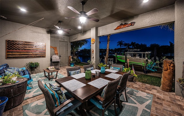 patio at twilight with outdoor dining space, area for grilling, and a ceiling fan