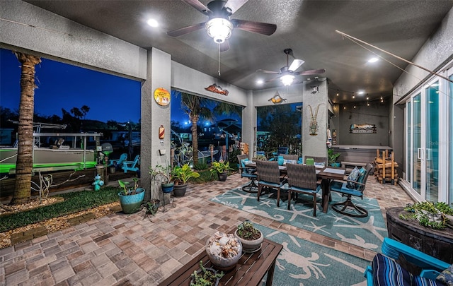 patio at night with a ceiling fan and outdoor dining space