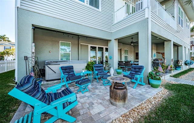 view of patio featuring a balcony, an outdoor fire pit, a hot tub, and fence