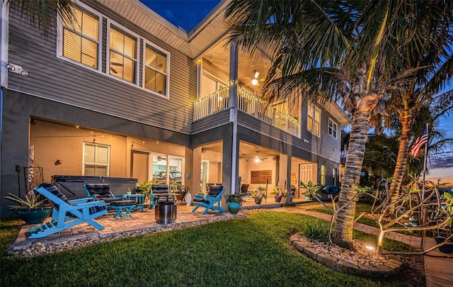 rear view of house with a yard, a patio, a balcony, and stucco siding