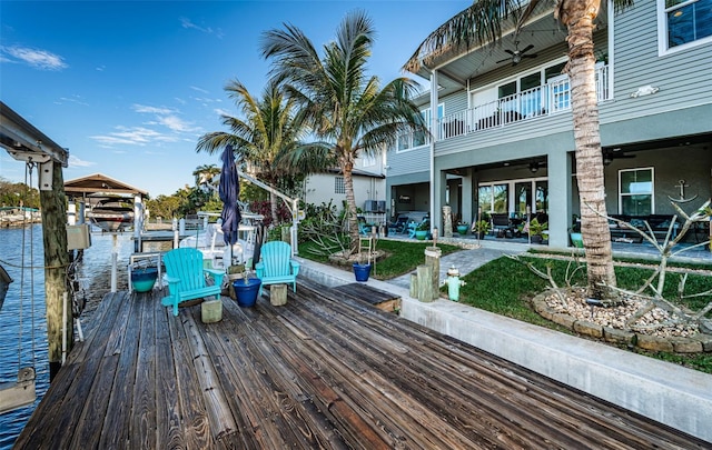 exterior space featuring a dock, a patio area, boat lift, and a ceiling fan