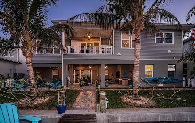 rear view of property with ceiling fan, a patio area, a balcony, and stucco siding