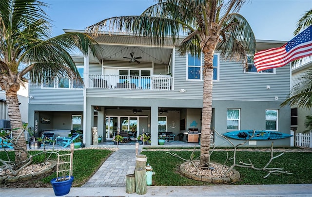 back of property with a ceiling fan, a balcony, fence, a patio area, and stucco siding