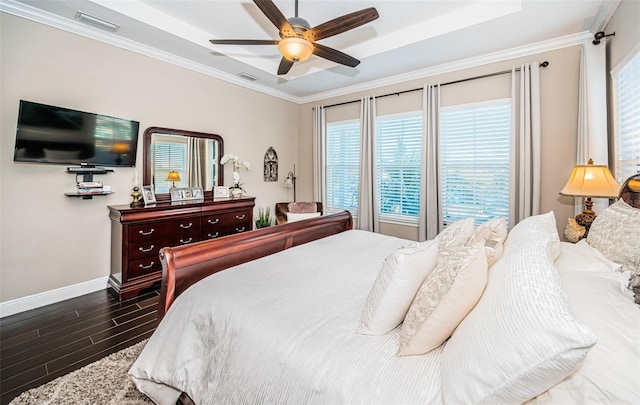 bedroom with baseboards, visible vents, crown molding, and wood finished floors