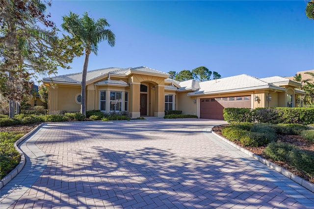 view of front of home with stucco siding, decorative driveway, and a garage